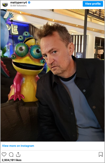 A man with short hair stands next to a colorful, multi-eyed statue resembling a frog, reminiscent of something from a Matthew Perry sitcom. The setting is indoors with bright lighting and blurred background elements, evoking the surreal effects of ketamine-induced art. - Ketamine